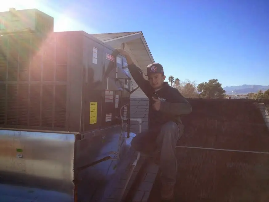HVAC technician performing AC Tune-Up on a rooftop unit in Hughson