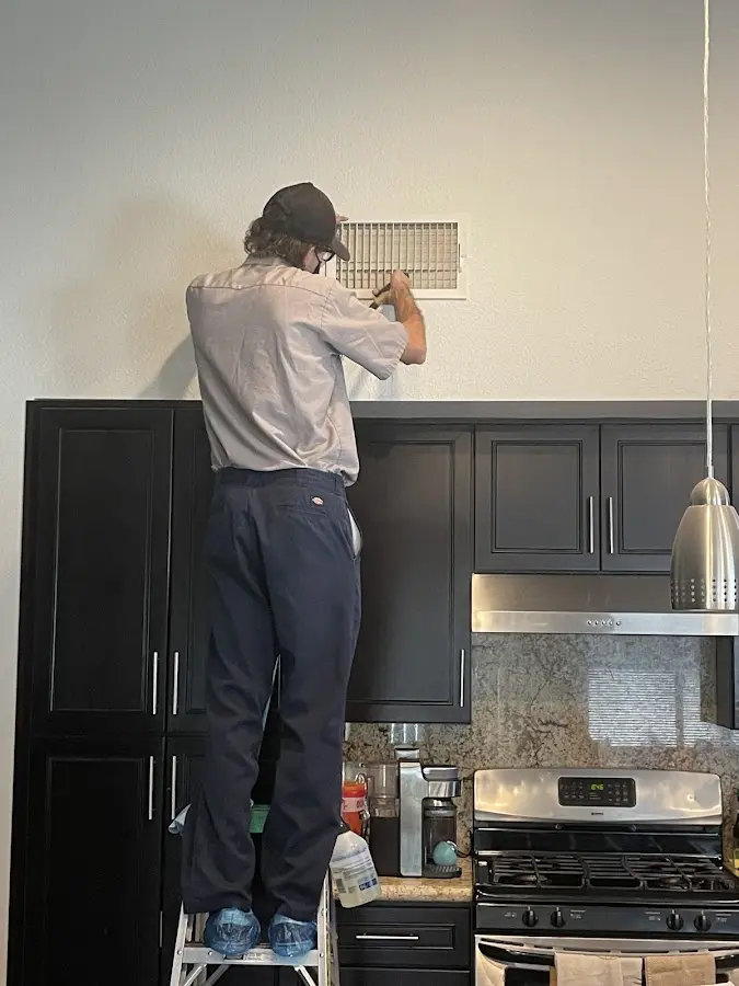 Technician inspecting an air vent during HVAC service in Hughson